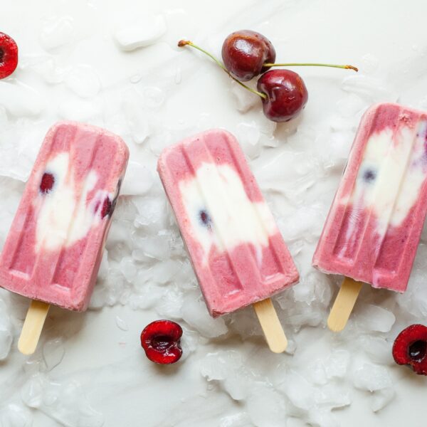 pink popsicles with cherries on ice background